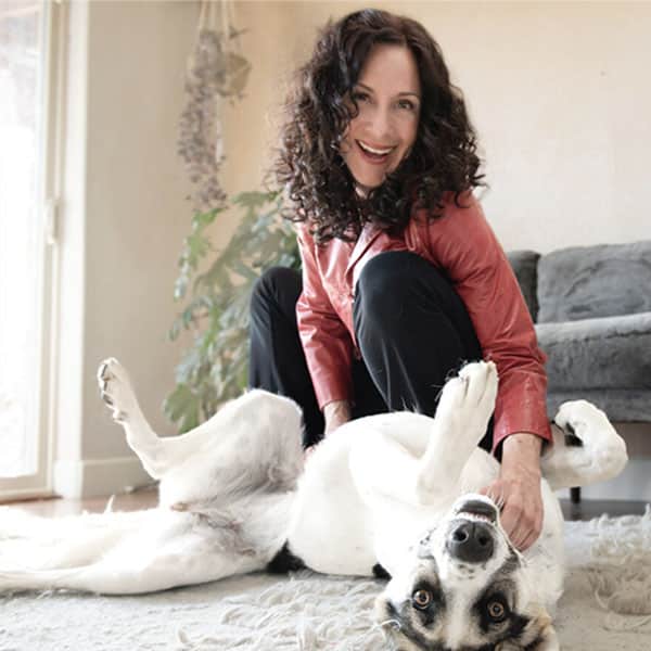 Woman smiling with her dog on the floor