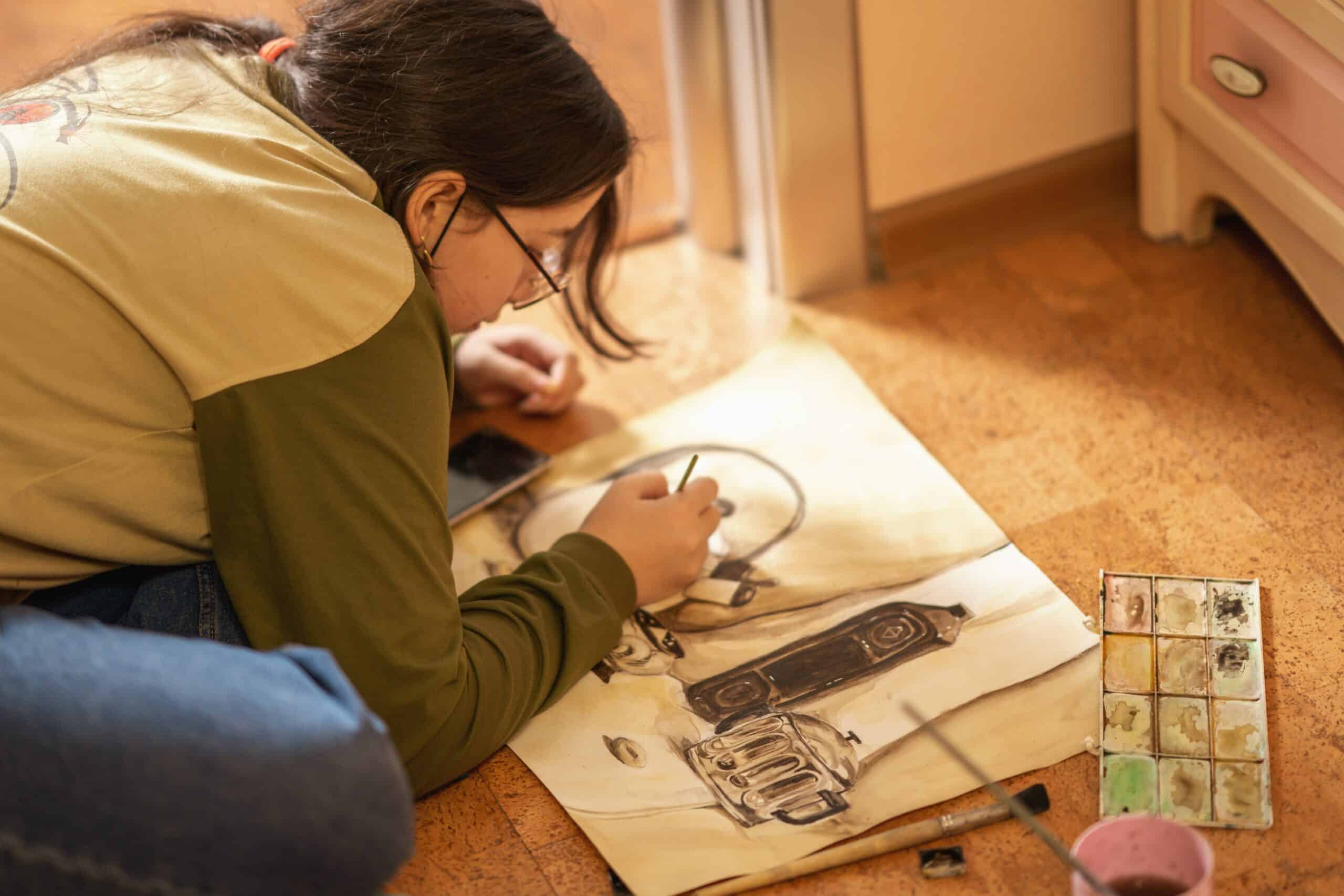 girl painting with paints on the floor