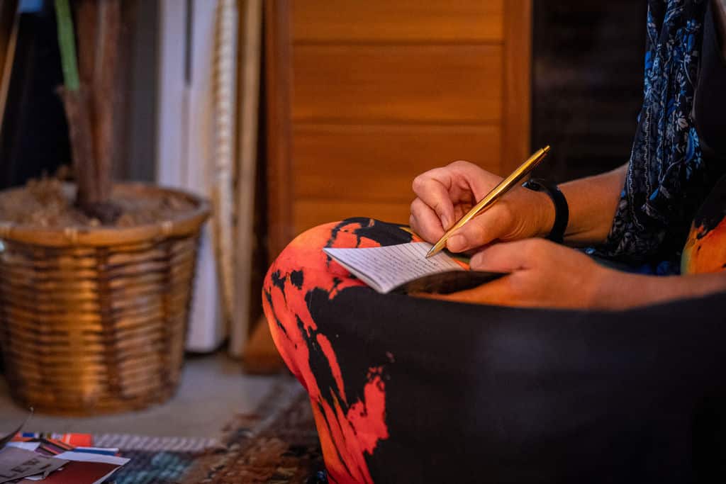 Person writing on paper for vessel during grief processing art therapy exercise